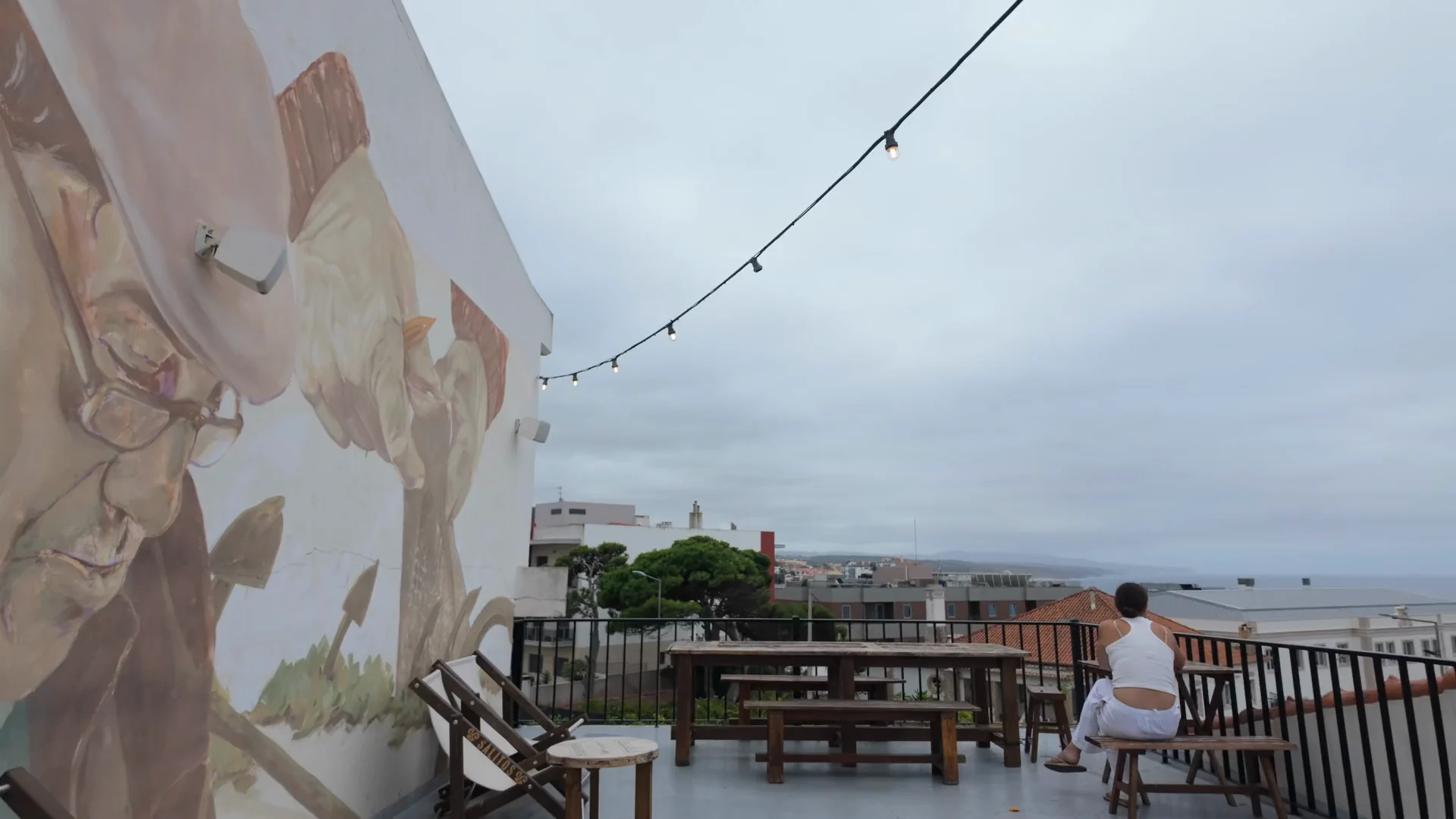 A guest sitting on an ocean-view terrace above the rooftops of Ericeira.